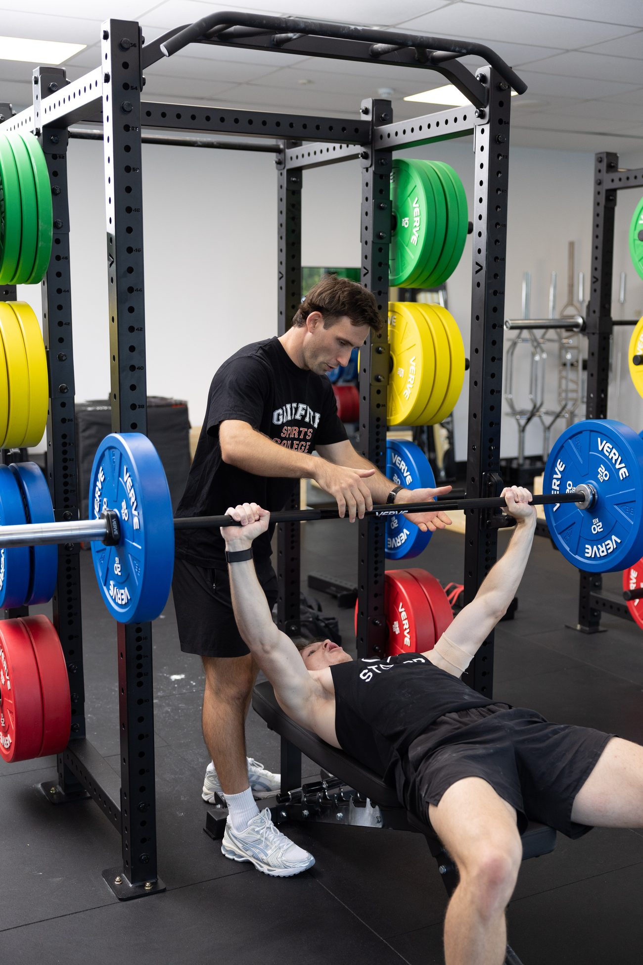 A coach spotting a barbell lift in a VERVE rack.