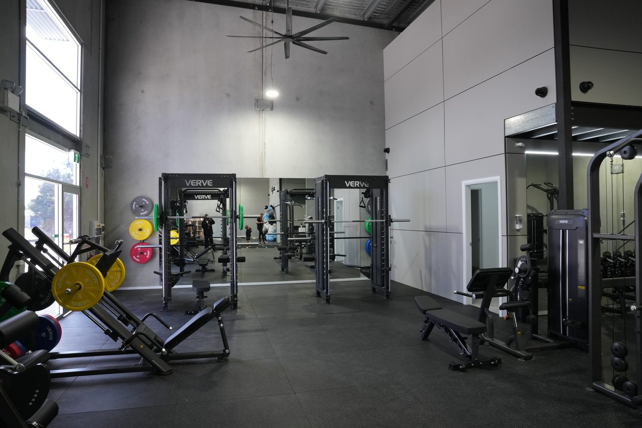 The Synergy RX strength floor — VERVE racks, leg press and machines in a raw concrete space.